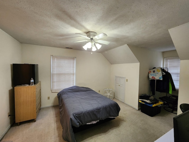 bedroom with lofted ceiling, light colored carpet, a textured ceiling, and ceiling fan