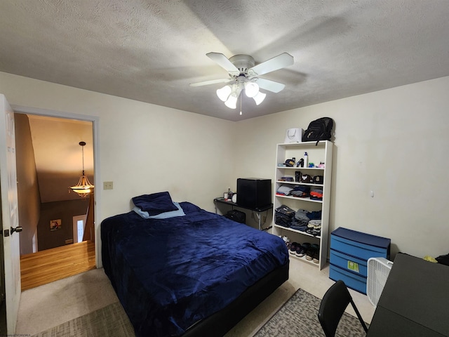 carpeted bedroom featuring ceiling fan and a textured ceiling