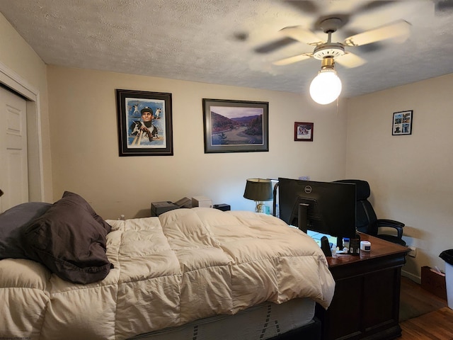 bedroom featuring ceiling fan, dark hardwood / wood-style floors, and a textured ceiling