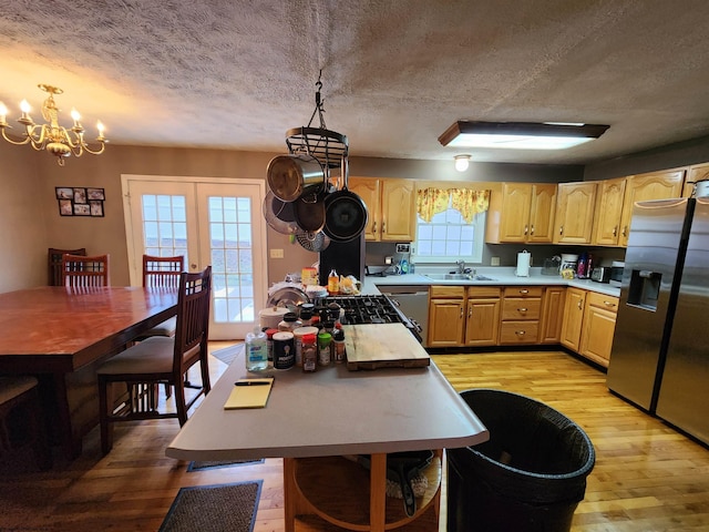 kitchen featuring sink, decorative light fixtures, stainless steel appliances, and light wood-type flooring