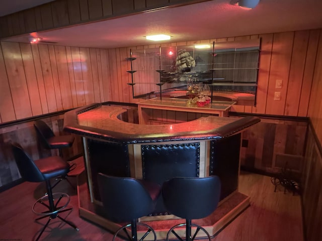 bar featuring hardwood / wood-style floors and wood walls