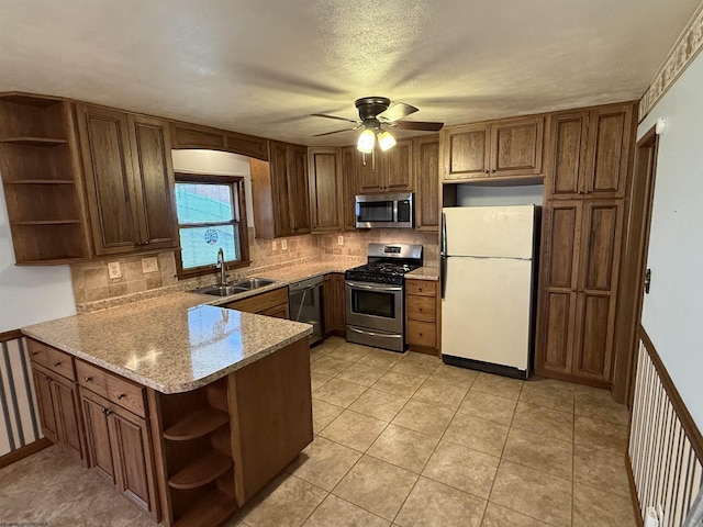 kitchen with sink, kitchen peninsula, stainless steel appliances, light stone countertops, and decorative backsplash