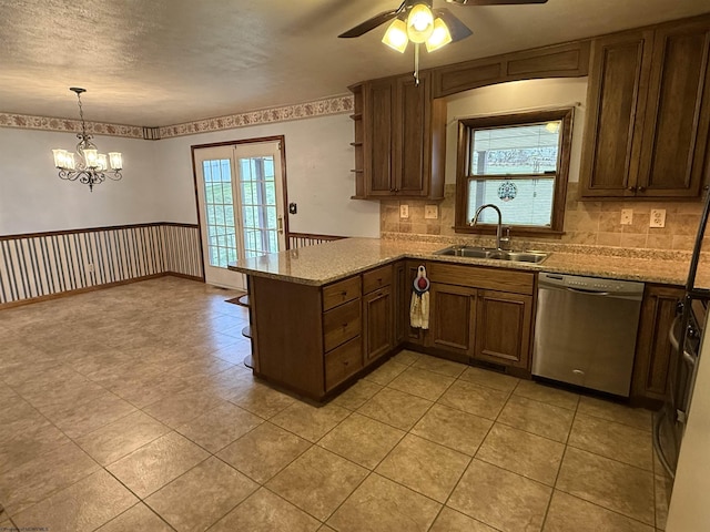 kitchen with sink, light stone counters, stainless steel dishwasher, kitchen peninsula, and pendant lighting