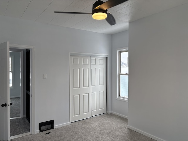 unfurnished bedroom with a closet, ceiling fan, and carpet flooring