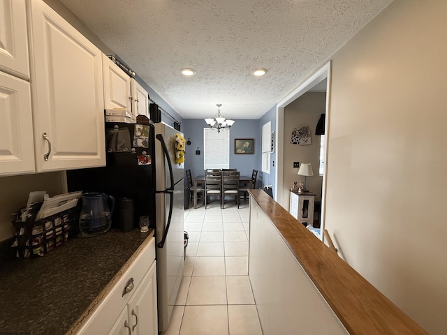 kitchen with white cabinetry, a textured ceiling, light tile patterned floors, a notable chandelier, and pendant lighting