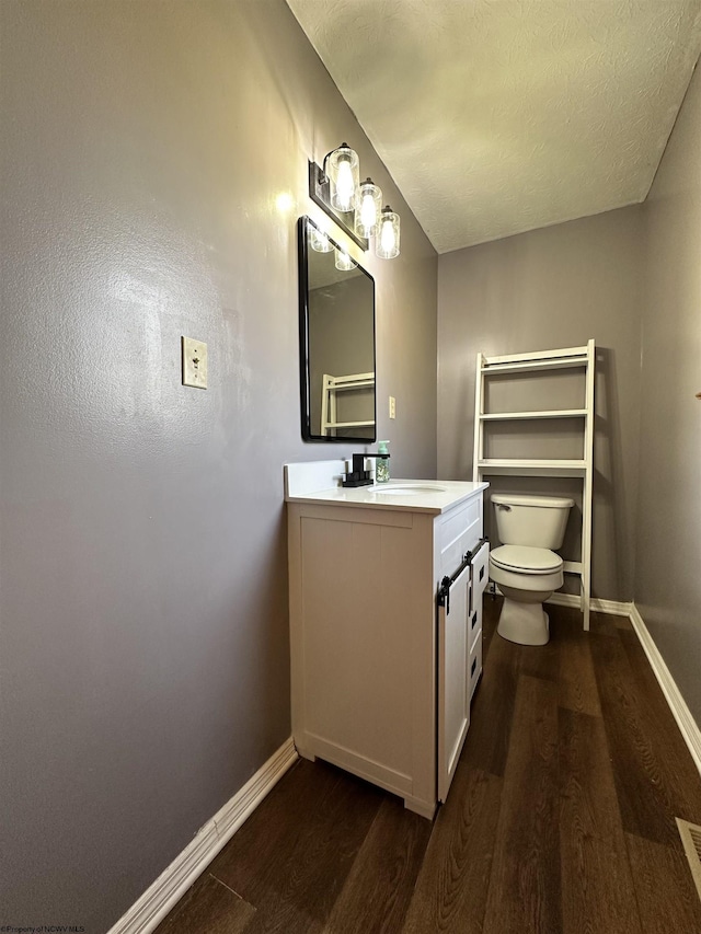 bathroom featuring vanity, hardwood / wood-style floors, a textured ceiling, and toilet