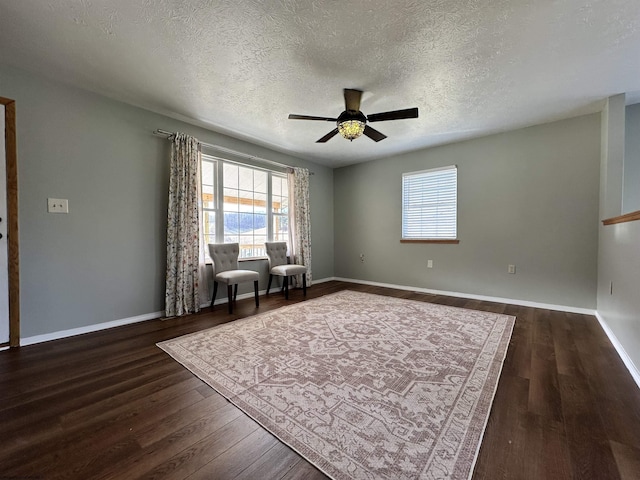 unfurnished room featuring ceiling fan, a healthy amount of sunlight, dark hardwood / wood-style flooring, and a textured ceiling