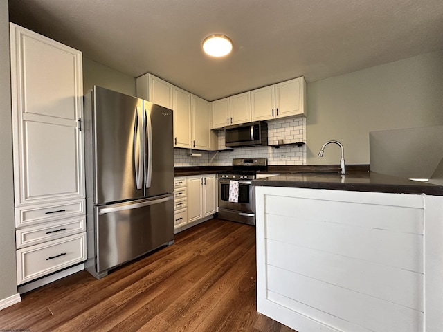 kitchen with appliances with stainless steel finishes, sink, white cabinets, and dark hardwood / wood-style floors