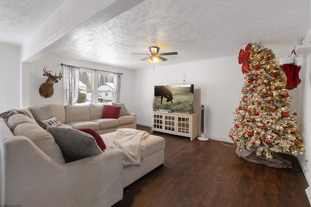 living room featuring ceiling fan, dark wood-type flooring, and a textured ceiling