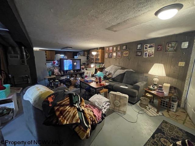 living room with concrete flooring, wooden walls, and a textured ceiling