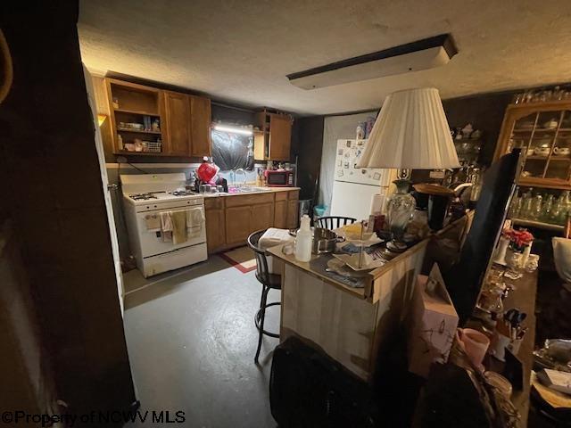 kitchen featuring white appliances, a breakfast bar area, and concrete flooring