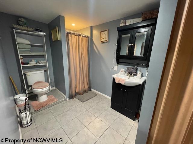 bathroom with walk in shower, tile patterned floors, vanity, and toilet