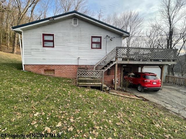 rear view of property with a garage, a wooden deck, and a yard