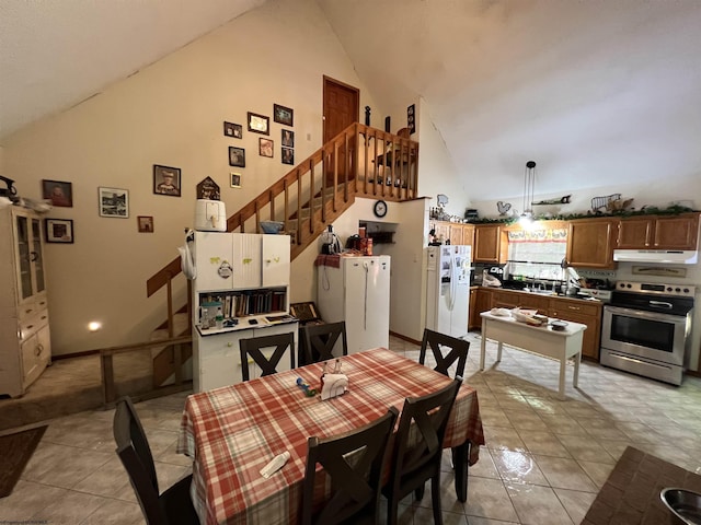 dining area with light tile patterned flooring and high vaulted ceiling