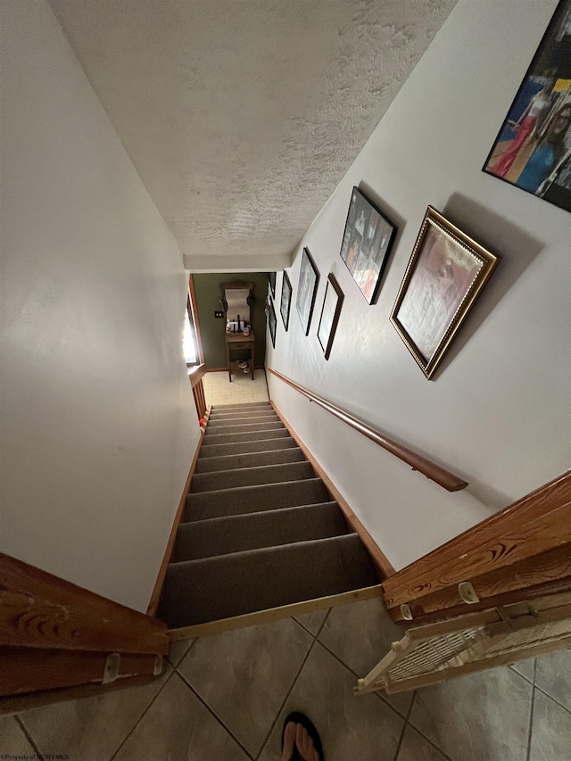 stairway with tile patterned flooring and a textured ceiling