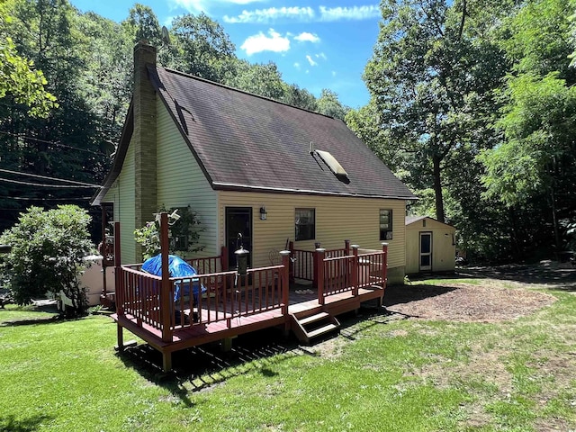 back of property with a wooden deck, a yard, and an outbuilding