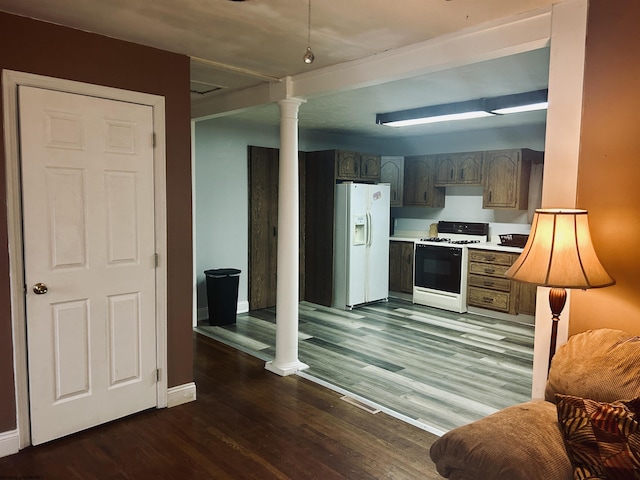 kitchen with dark hardwood / wood-style floors, white refrigerator with ice dispenser, decorative columns, and gas stove