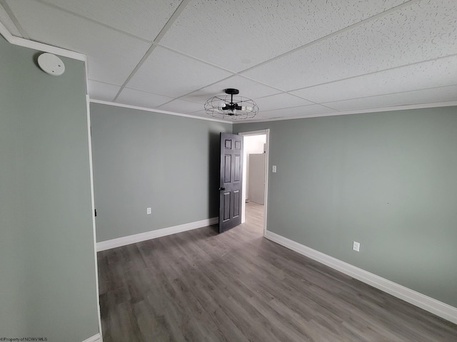 empty room with ornamental molding, a paneled ceiling, and hardwood / wood-style floors