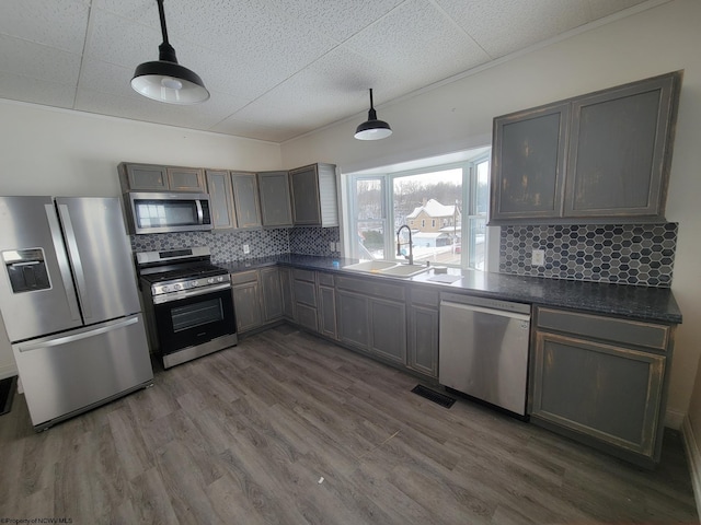 kitchen featuring stainless steel appliances, sink, pendant lighting, and dark wood-type flooring