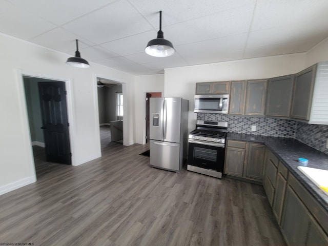 kitchen featuring tasteful backsplash, dark hardwood / wood-style flooring, dark stone countertops, and appliances with stainless steel finishes