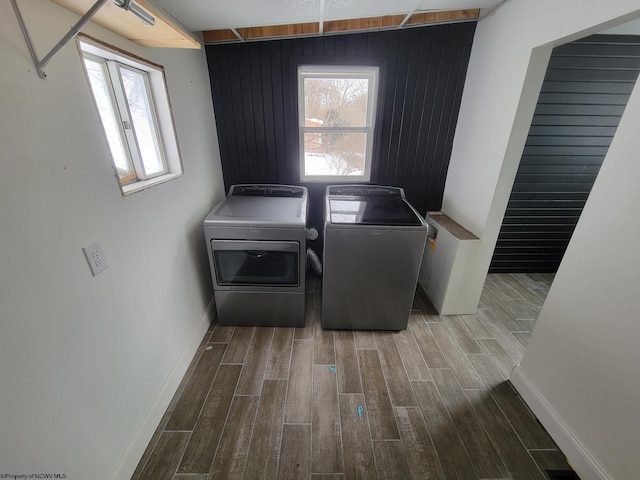 clothes washing area with washer and dryer and wood walls