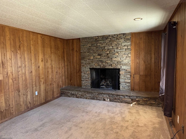 unfurnished living room with carpet, wooden walls, and a fireplace