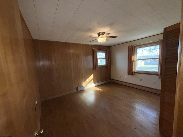 empty room with hardwood / wood-style flooring, ceiling fan, and wood walls