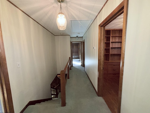 hall with light carpet, crown molding, and built in shelves