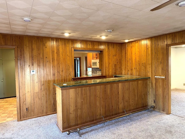 bar featuring wooden walls, light colored carpet, and ceiling fan