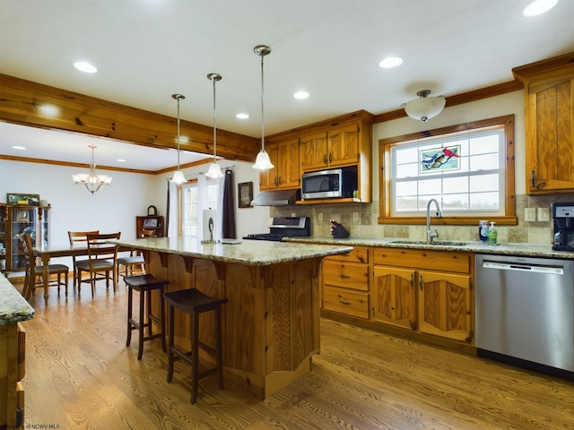 kitchen featuring stainless steel appliances, a kitchen island, sink, and decorative light fixtures