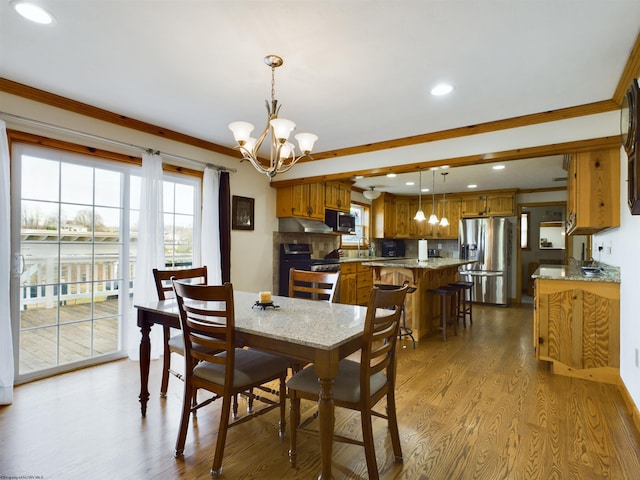 dining space with ornamental molding, sink, a notable chandelier, and light wood-type flooring