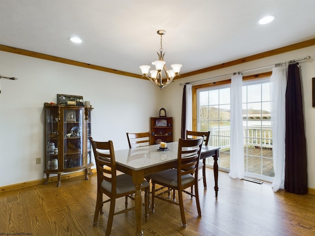 dining area with crown molding, hardwood / wood-style floors, and a notable chandelier