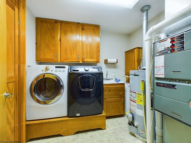 laundry room featuring heating unit, gas water heater, cabinets, and washing machine and clothes dryer