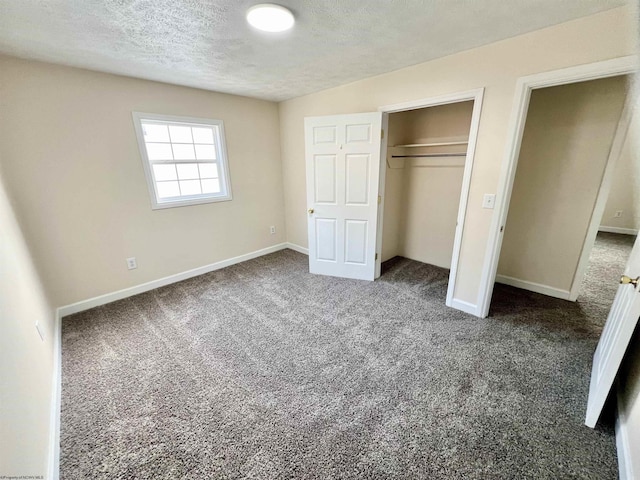 unfurnished bedroom featuring a textured ceiling, dark carpet, and a closet