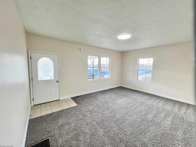 carpeted foyer featuring a textured ceiling