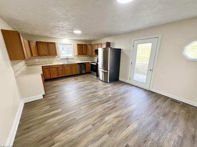 kitchen featuring appliances with stainless steel finishes, sink, backsplash, and light hardwood / wood-style flooring