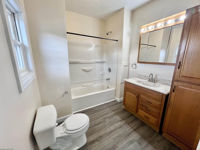 full bathroom with toilet, wood-type flooring, a textured ceiling, shower / bathtub combination, and vanity