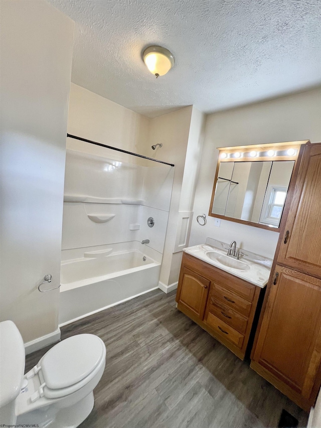 full bathroom with shower / bathing tub combination, hardwood / wood-style flooring, vanity, toilet, and a textured ceiling