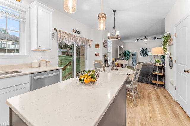 kitchen with pendant lighting, sink, dishwasher, white cabinetry, and light hardwood / wood-style floors