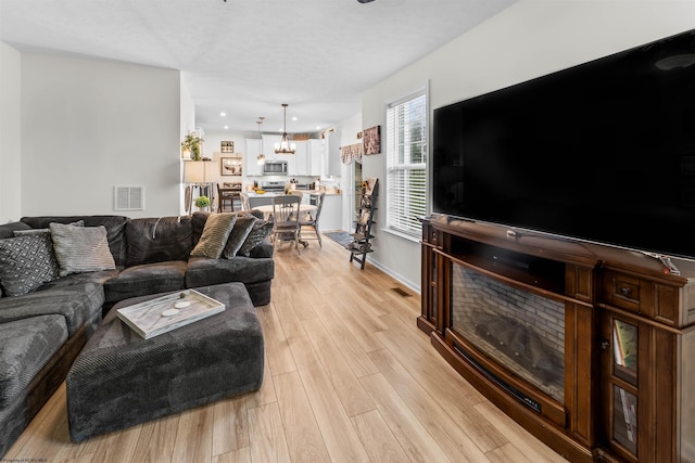 living room with a notable chandelier and light hardwood / wood-style floors