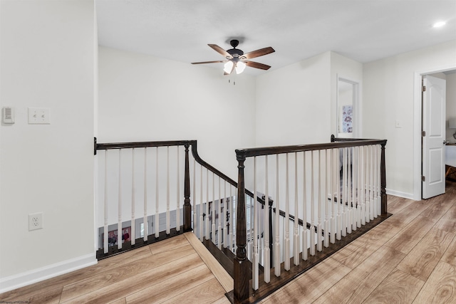 stairs featuring hardwood / wood-style flooring and ceiling fan