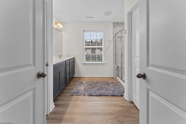 bathroom with vanity, hardwood / wood-style flooring, and a shower with door