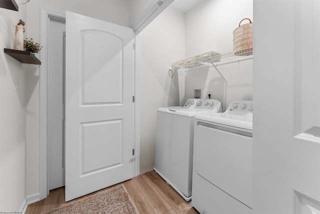 clothes washing area with washer and clothes dryer and light hardwood / wood-style floors