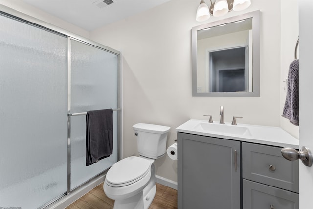 bathroom featuring vanity, hardwood / wood-style floors, a shower with shower door, and toilet