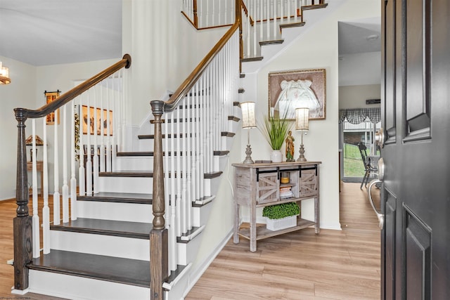 stairway featuring hardwood / wood-style flooring, a chandelier, and a high ceiling