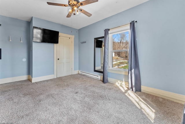 spare room featuring ceiling fan, carpet, and a baseboard heating unit