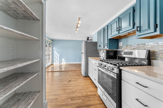 kitchen featuring ceiling fan, backsplash, stainless steel appliances, light hardwood / wood-style floors, and blue cabinets