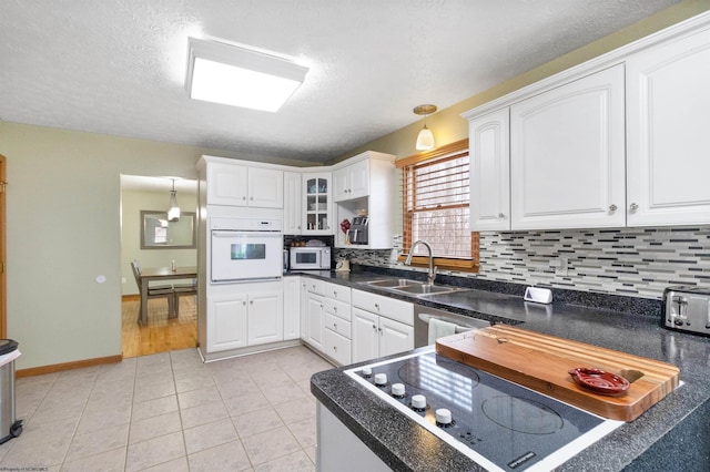 kitchen featuring pendant lighting, white cabinetry, sink, decorative backsplash, and white appliances