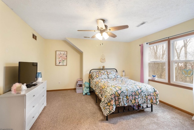 bedroom featuring ceiling fan, light carpet, and a textured ceiling