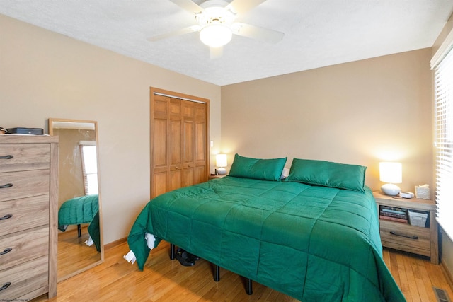 bedroom featuring multiple windows, ceiling fan, a closet, and light wood-type flooring